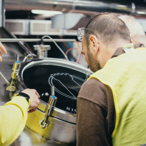 Operai al lavoro vicino a una cisterna di birrificazione di Birra del Borgo.